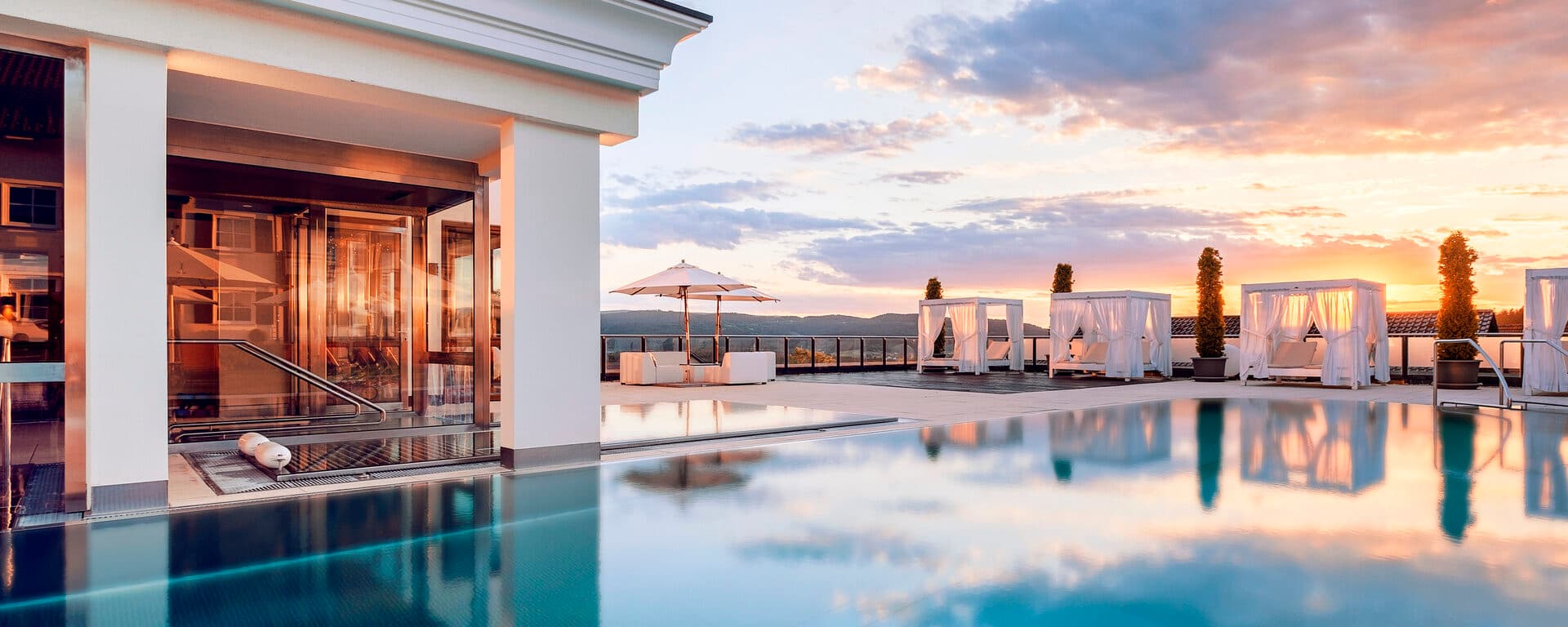 Dachschwimmbad mit Liegen im Sonnenuntergang, Hotel Oswald